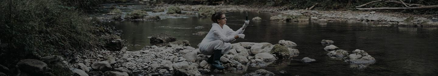 Scientist woman at a river collecting water samples