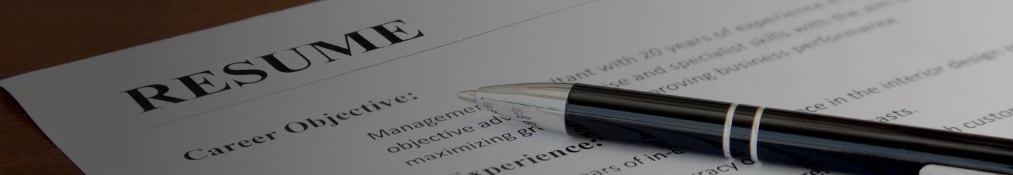 A resume laying on a table with a pen over it.