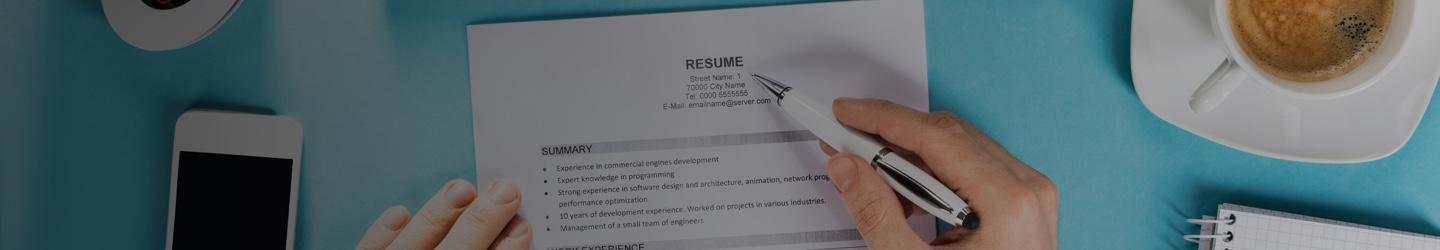 Male hands holding a resume and revising it with a pen.