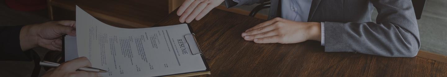 Two businesspeople reviewing a resume on a clipboard.