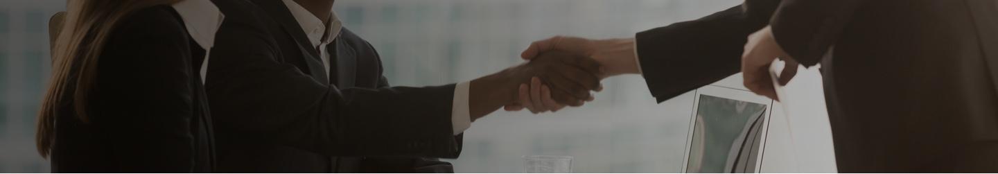 Two businesspeople shake hands in a conference room.