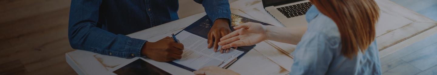 Business woman shaking hands with a businessman over a desk at an office