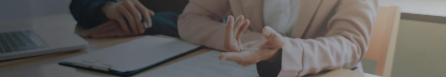 View of hands of businesspeople having a conversation at a table with a resume and other documents.