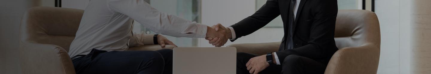 Two businessmen shaking hands at an office desk.