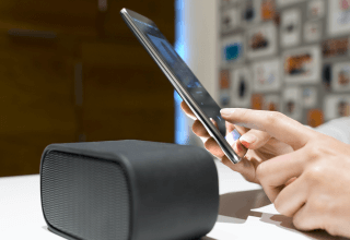 Woman setting her smartphone to connect with a wireless speaker