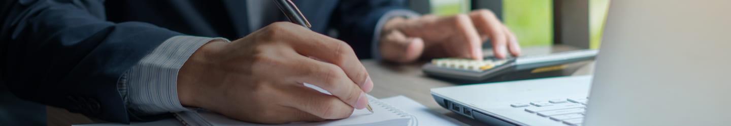 Man using a calculator and writing on a paper.