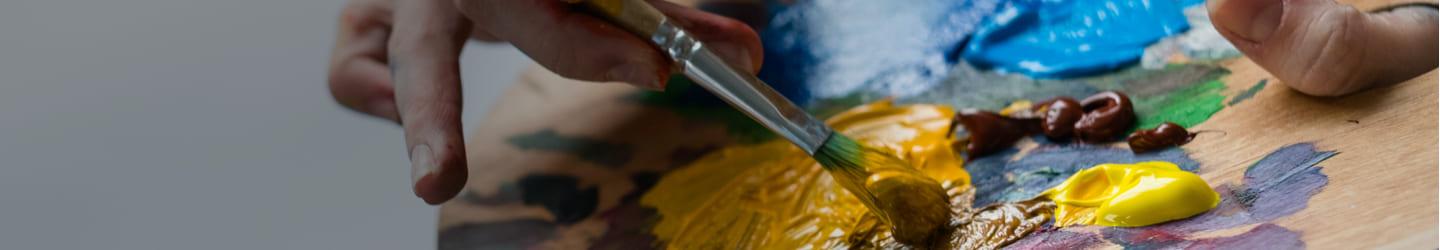 Painter mixing colors on a color palette with a brush