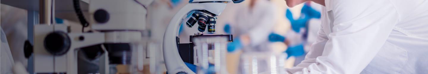 Scientist in a lab looking through a microscope