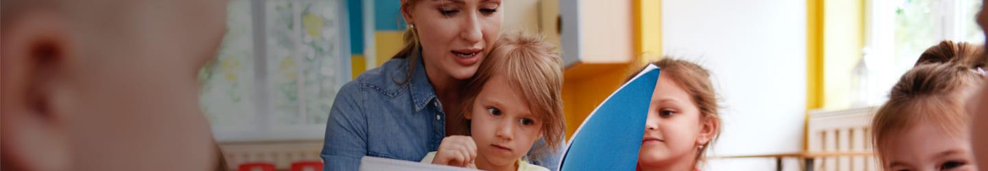 Teacher reading a book to two students