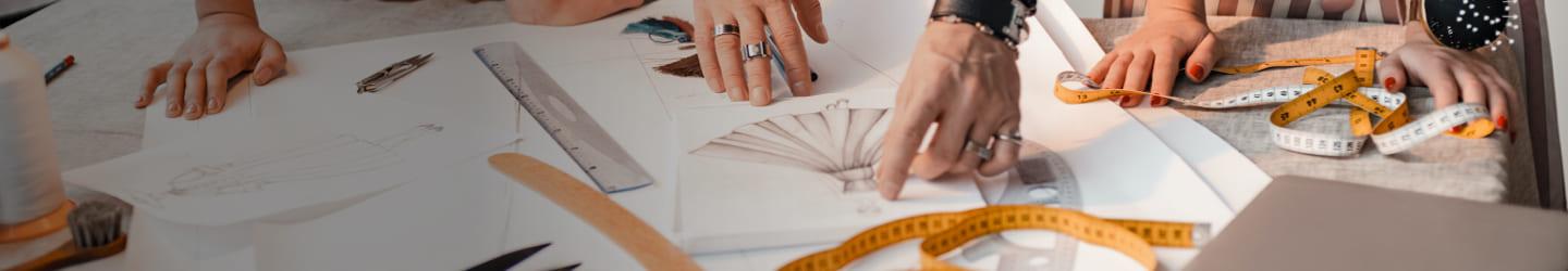 Group of designers looking at clothing drawings with meassuring tape