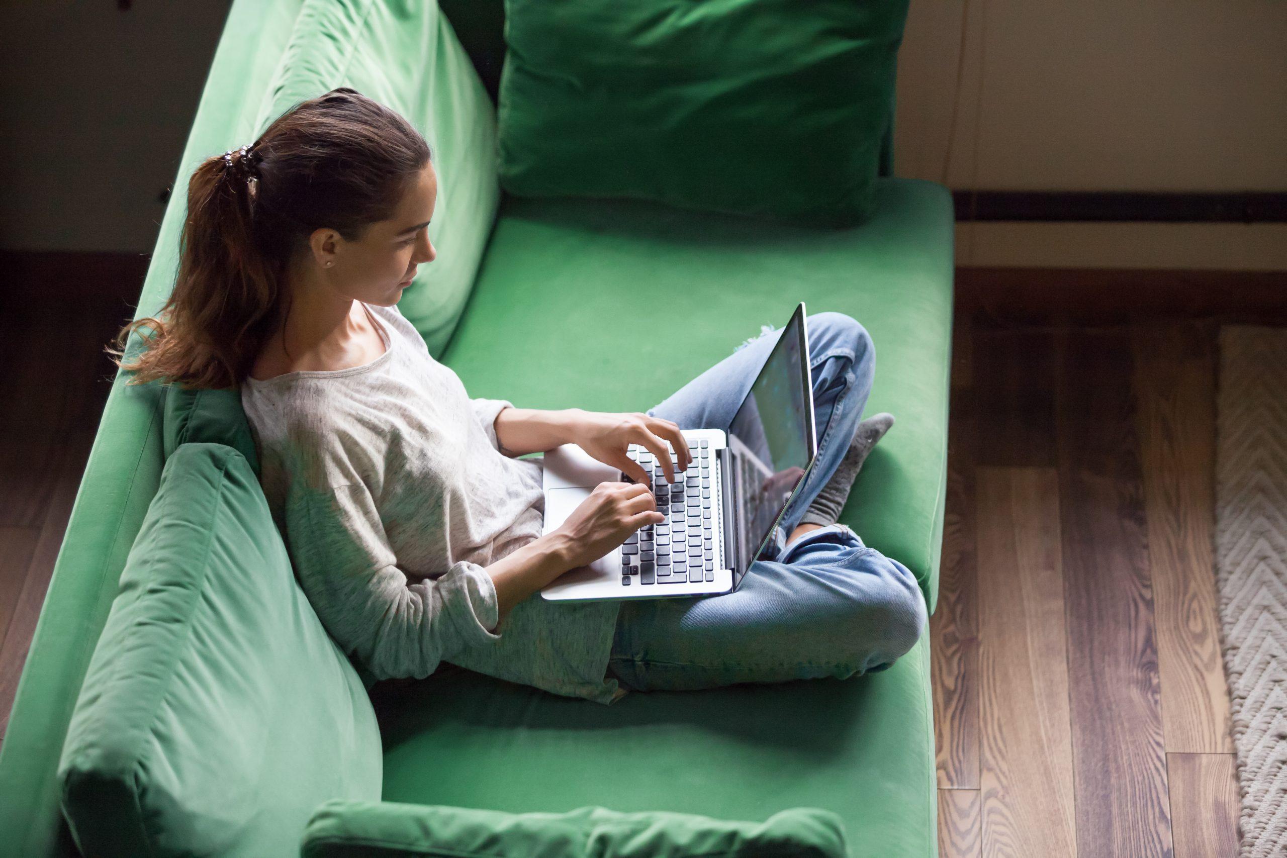 woman sitting on sofa while browsing on the computer