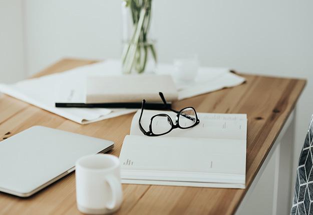 Workplace with books, eyeglasses and laptop