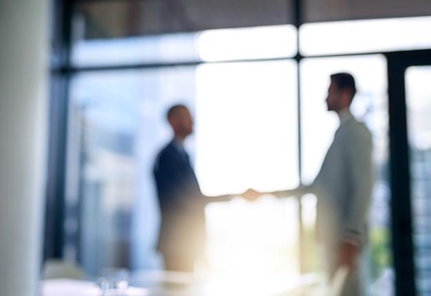 Two businessmen shaking hands out of focus