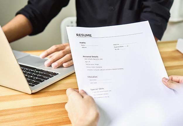 Person holding a resume. Man using a laptop
