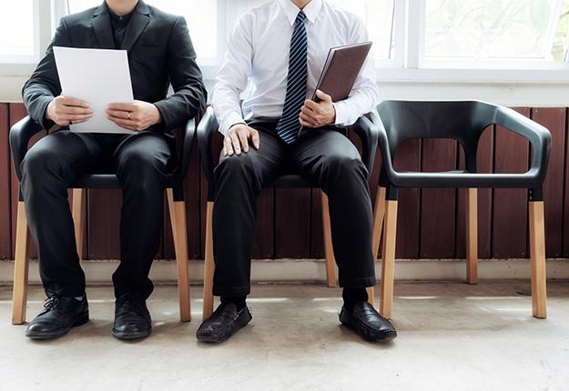 Two businessmen waiting in lobby holding paper and notebook