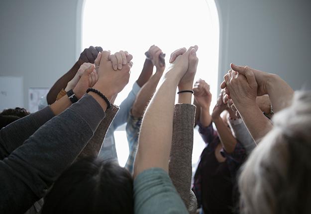 Multi-racial people holding hands up in support
