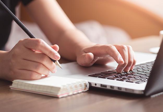 Woman writting on computer and notepad