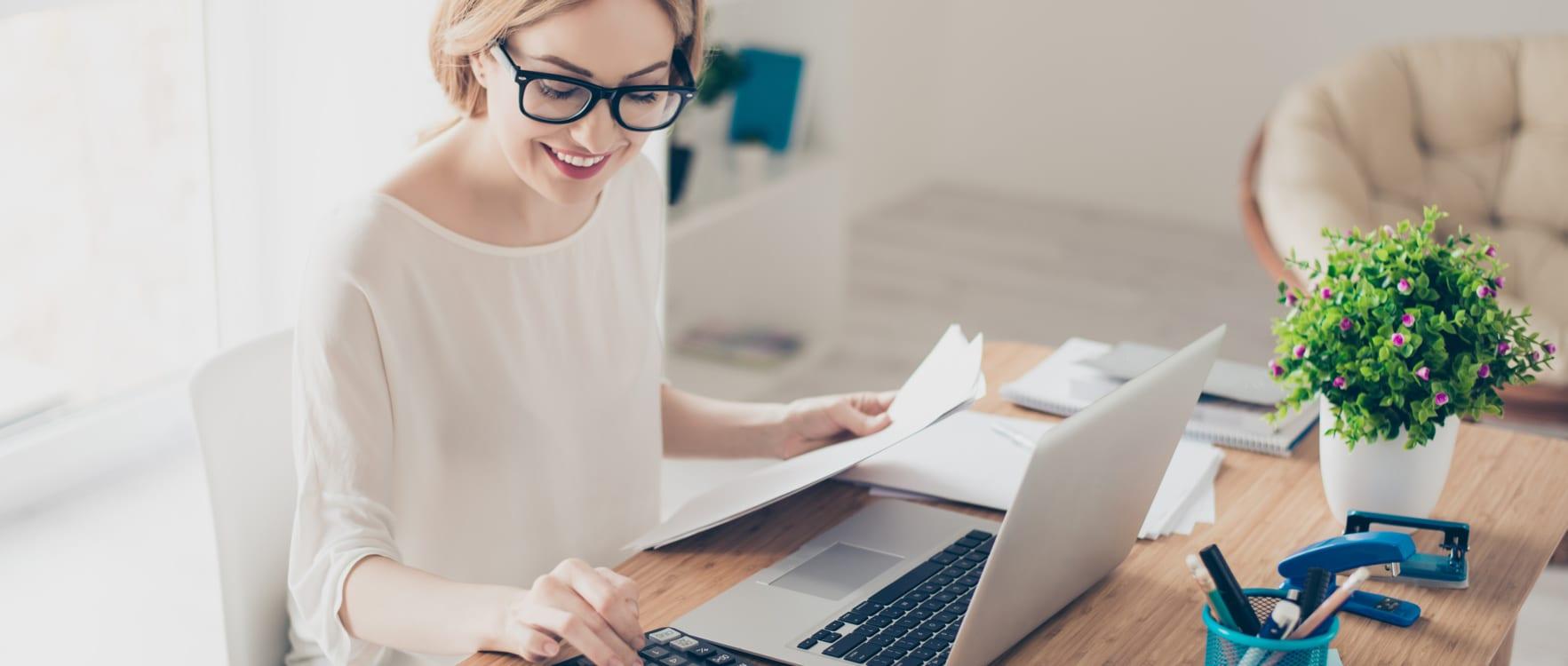 Woman working on a desk with a laptop and a calculator