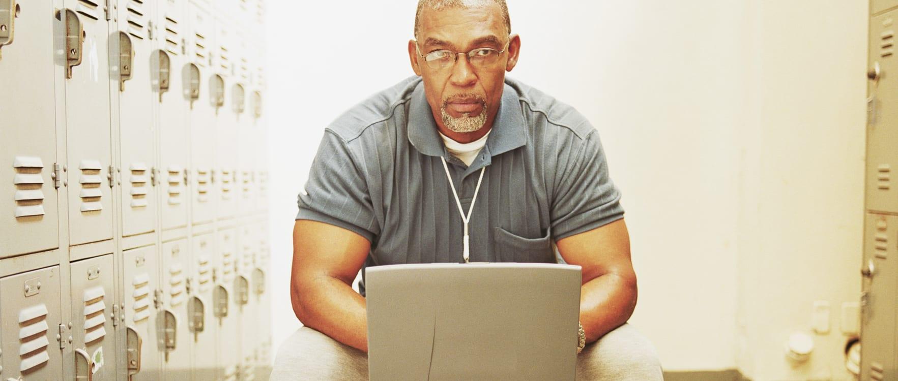 Middle-aged man working on a laptop in a locker room