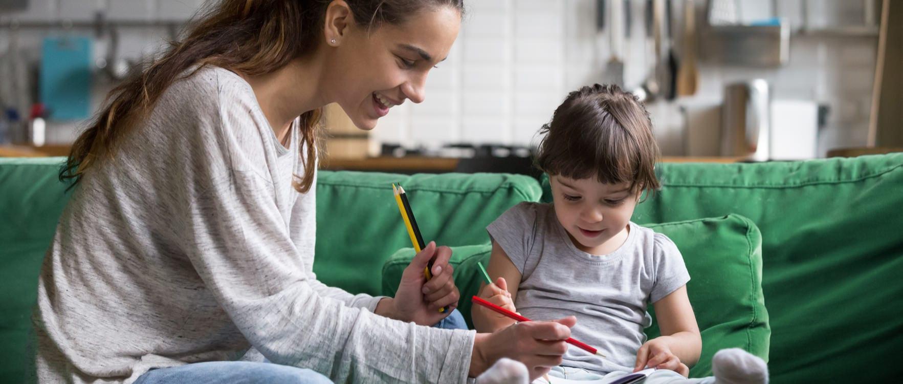Young babysitter helping a little girl color a coloring book