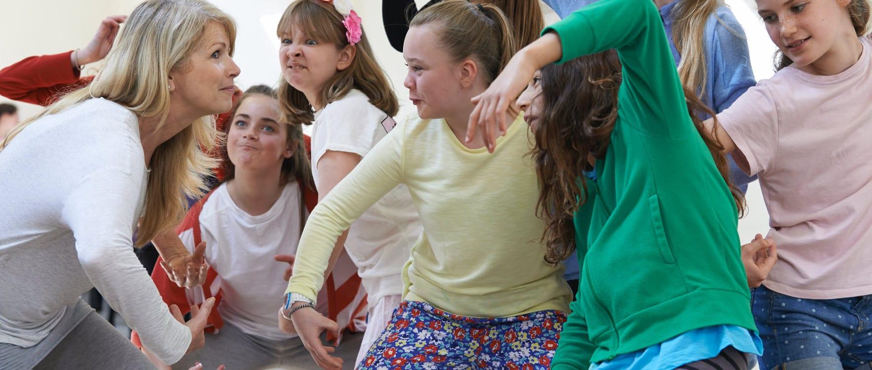 Woman teaching dramatic gestures to a group of young girls