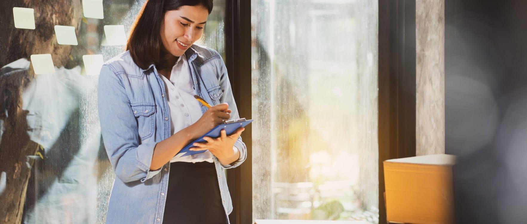 Woman taking notes while standing in front of a box