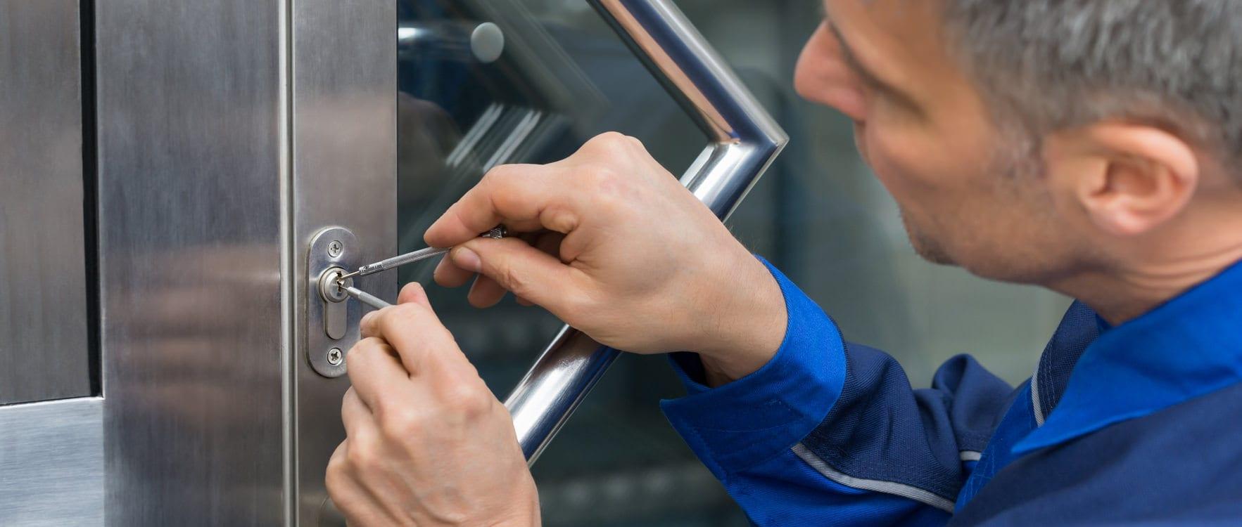Man in uniform picking a lock with locksmith tools