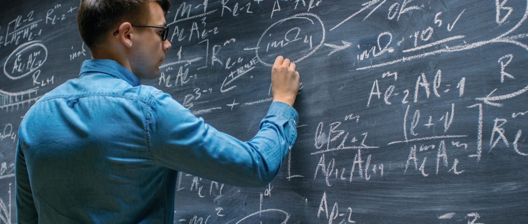 Man writing math equations on a blackboard
