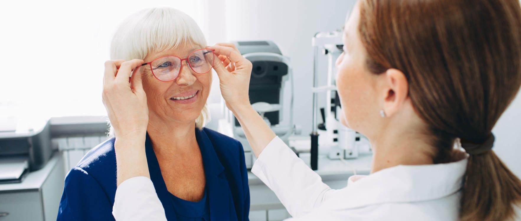 Female optician putting on glasses on a lady