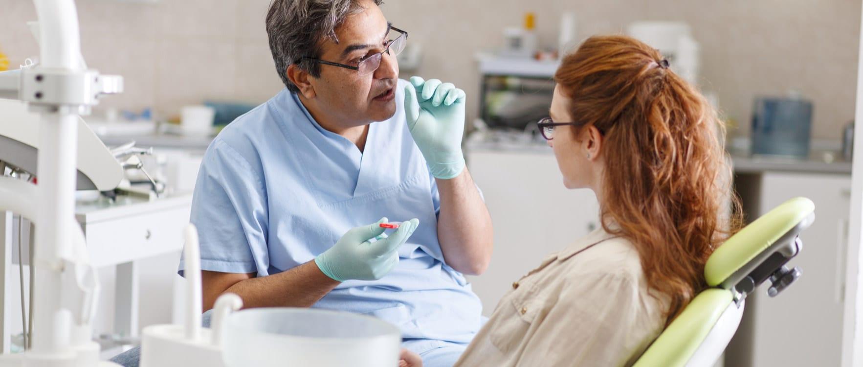 Male orthodontist talking to a female patient in an operating room