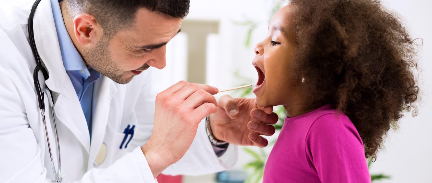 Doctor examining little girl's tonsils