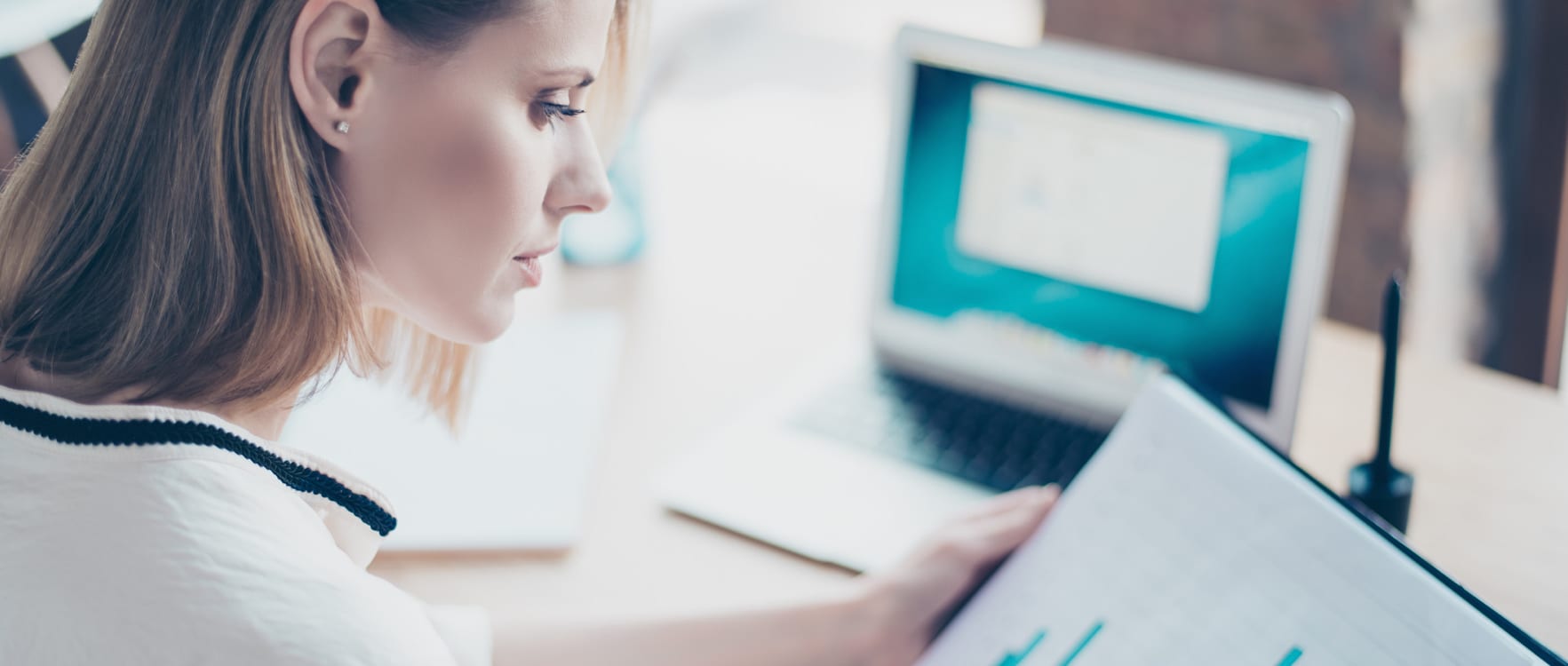 Woman reviewing charts on paper and on her laptop