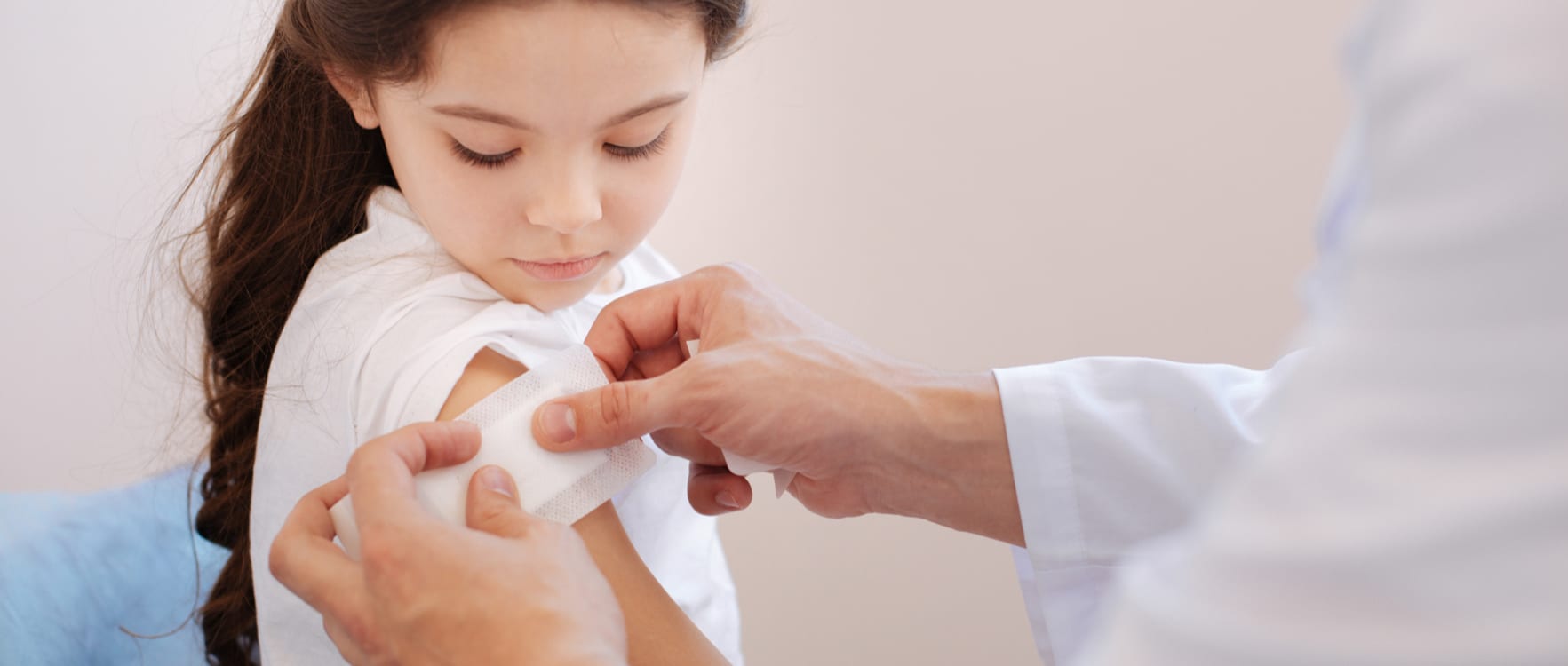 Male nurse putting a bandage on a girl's arm