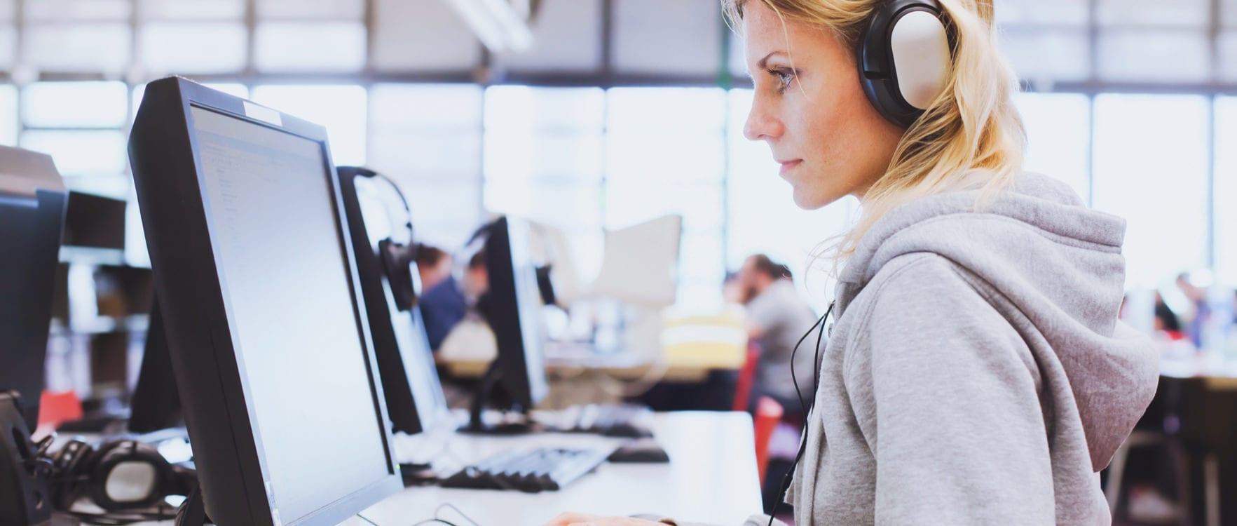 Woman with headphones working with a computer in a computer room