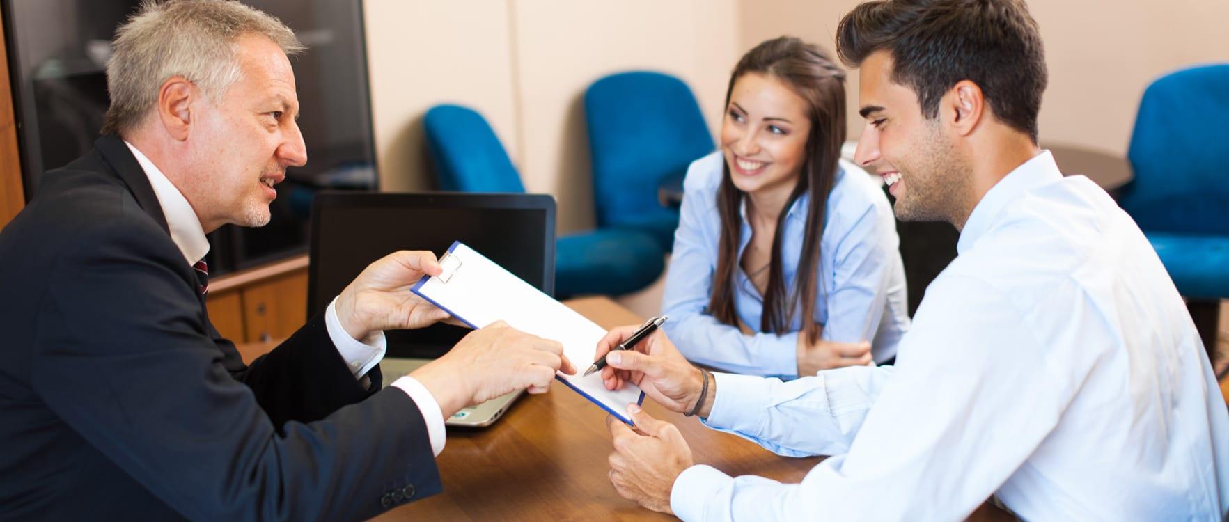 Couple signing an agreement with a businessman
