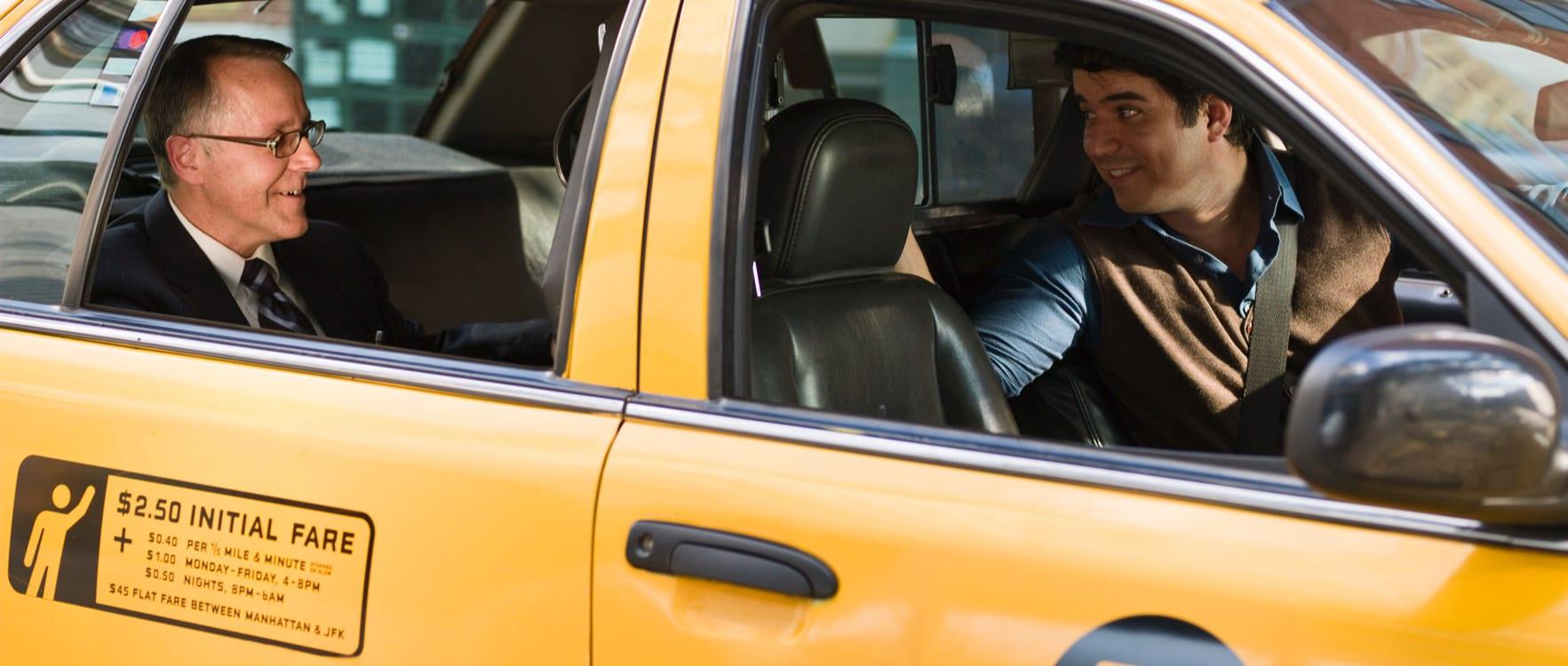 Taxi driver talking to his passenger in the backseat