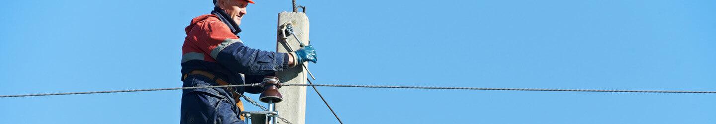 electrician working on electric power pole with blue sky