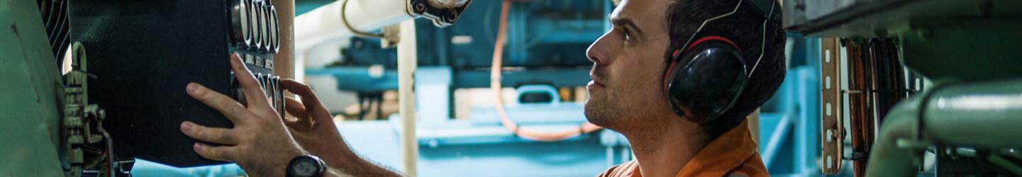 Marine Engineer working on machine with headphones