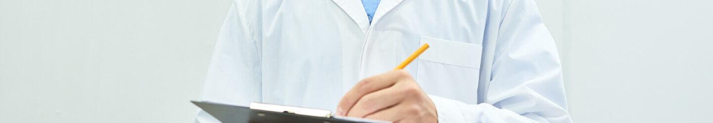 Doctor in a white coat writing something on a clipboard