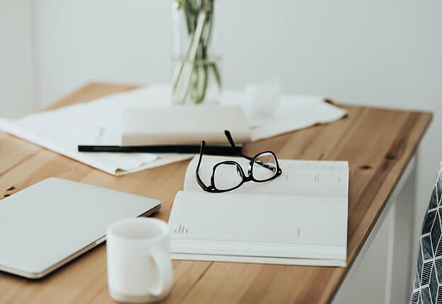 Workplace with books, eyeglasses and laptop