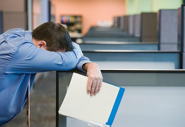 Businessman leaning on wall with head down