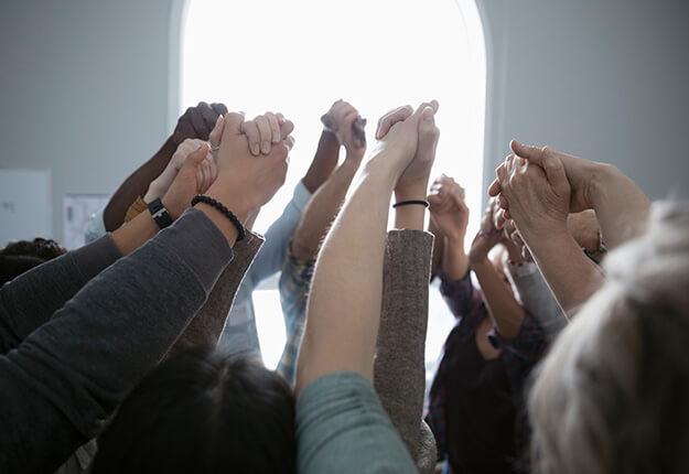 Multi-racial people holding hands up in support