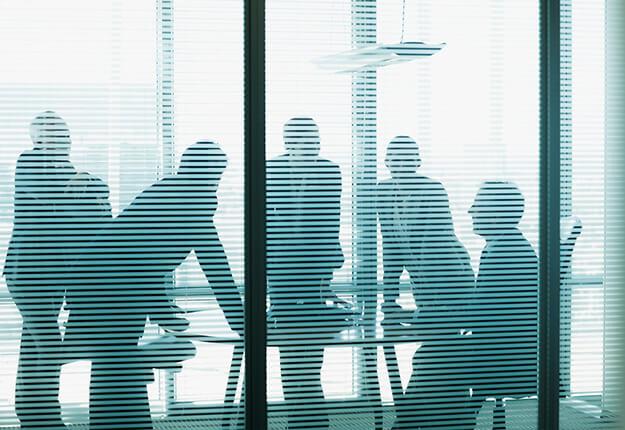 ilouhette of business people in office behind courins