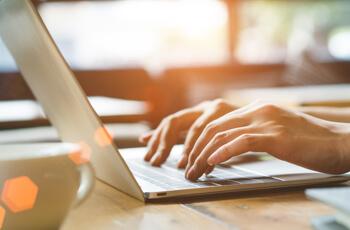 Woman hands typing on a laptop at a desk