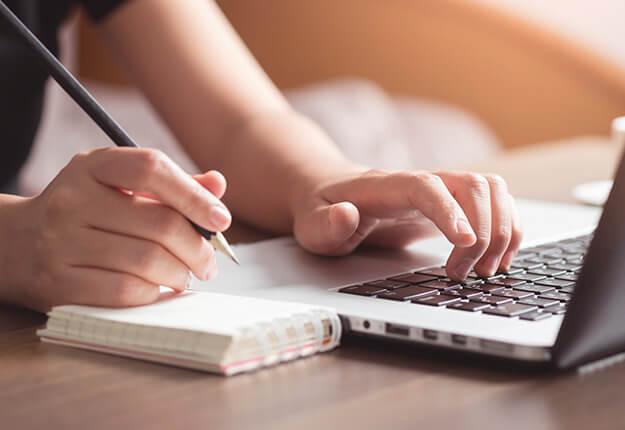 Woman writting on computer and notepad