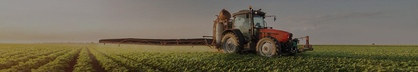 Tractor spraying pesticides on soybean field