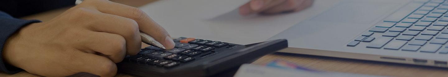 Man at his desk using a calculator and revising a bill