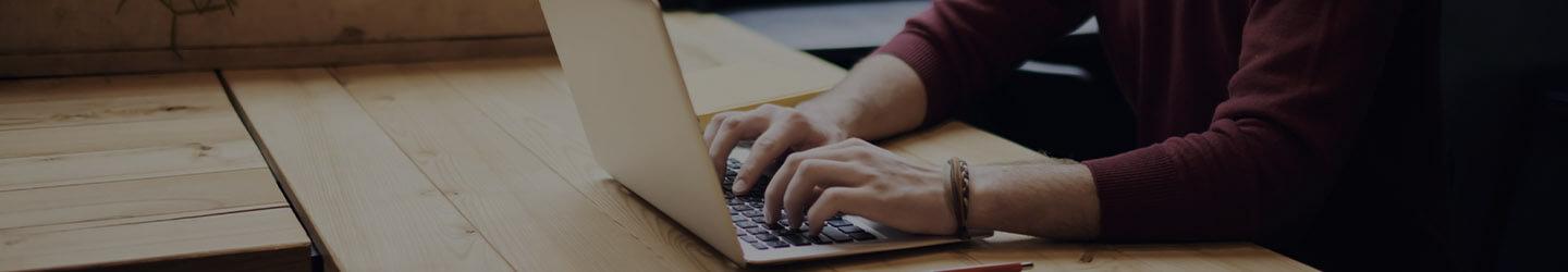 Man at a desk writing on his laptop