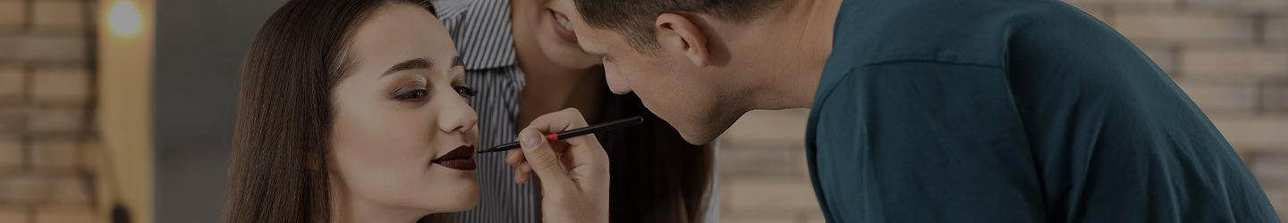 Male beauty technician applying makeup to a woman model