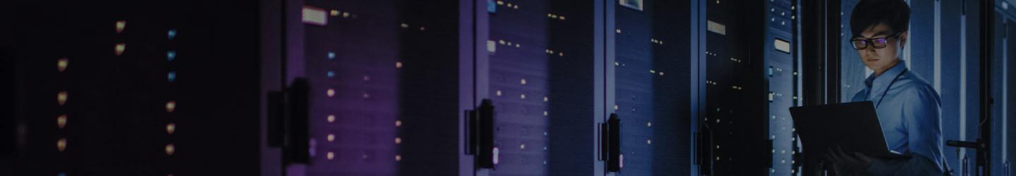 Technician holding a laptop while standing in a server room